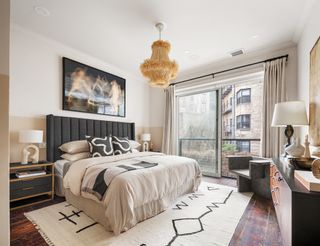 modern bedroom with color blocking on walls, raffia pendant light, white and black rug, and console with lamp