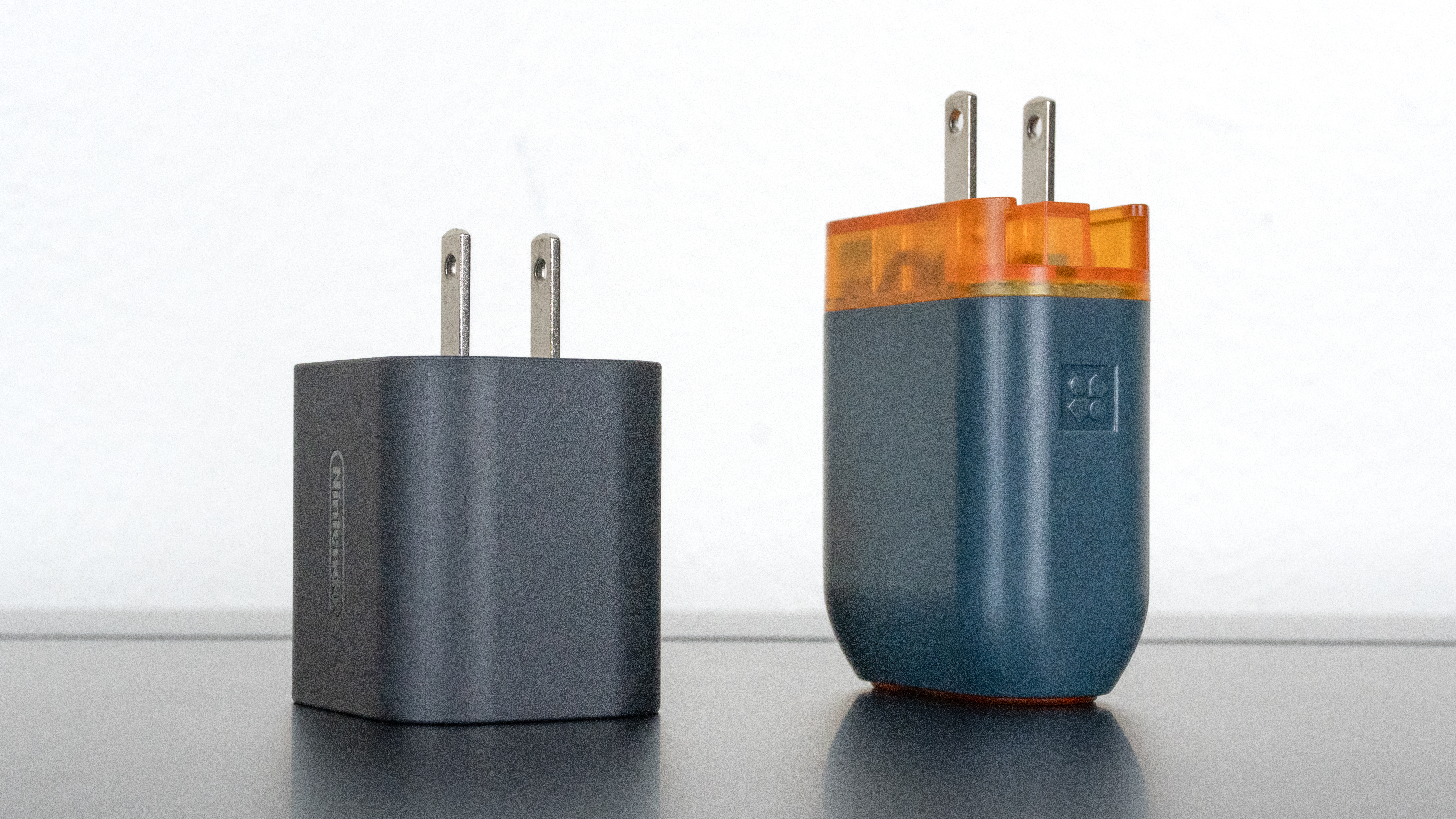 An official Nintendo Switch 2 power adapter next to the Genki Covert Dock 3 showing the size difference between the two