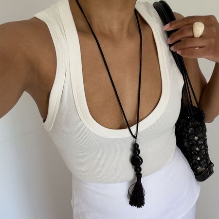 Woman in a tank top and black long necklace