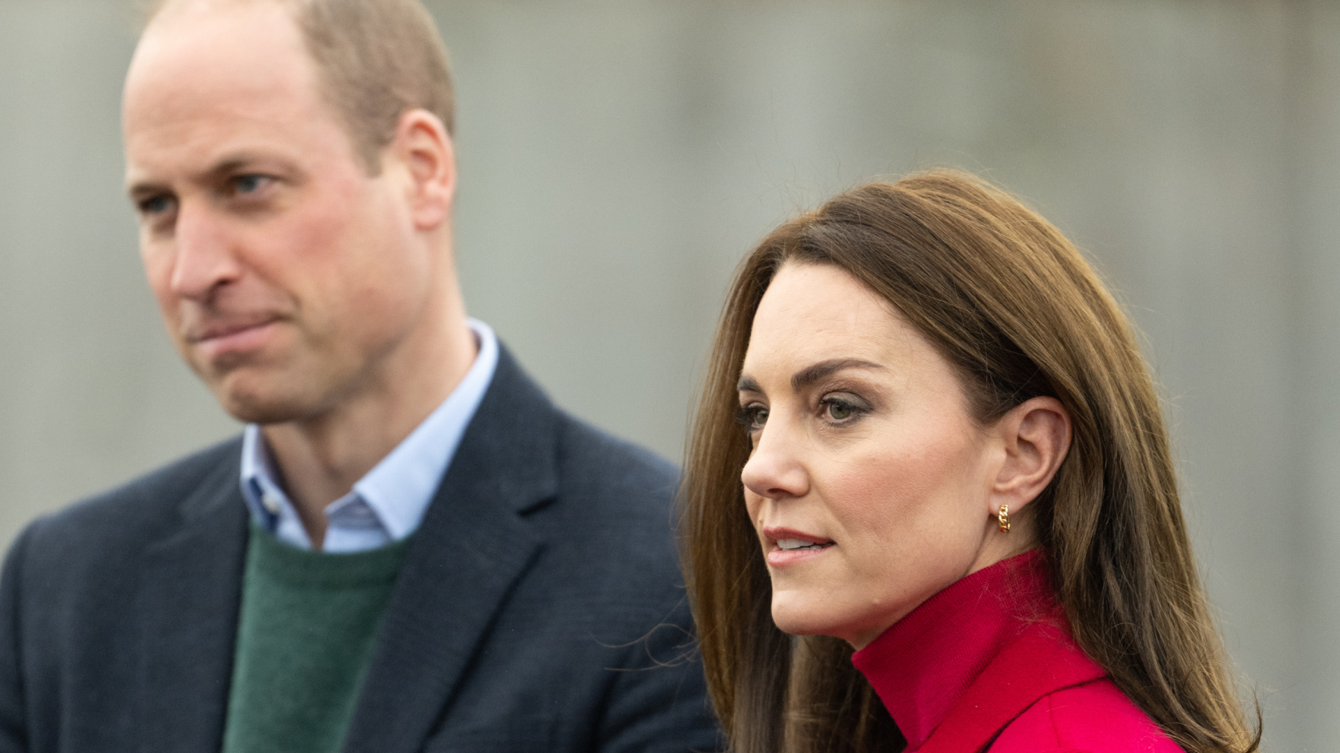 Prince William wears a navy coat and Kate Middleton wears a bright red coat and matching polo neck