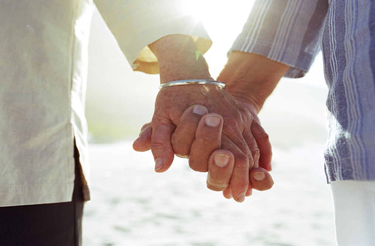 Elderly couple holding hands, close-up of hands