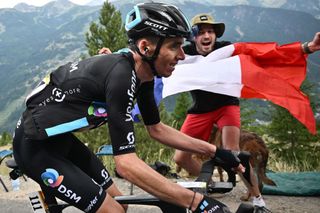 A spectator reacts with a French flag as Team DSM teams French rider Romain Bardet L cycles during the 11th stage of the 109th edition of the Tour de France cycling race 1517 km between Albertville and Col du Granon Serre Chevalier in the French Alps on July 13 2022 Photo by Marco BERTORELLO AFP Photo by MARCO BERTORELLOAFP via Getty Images