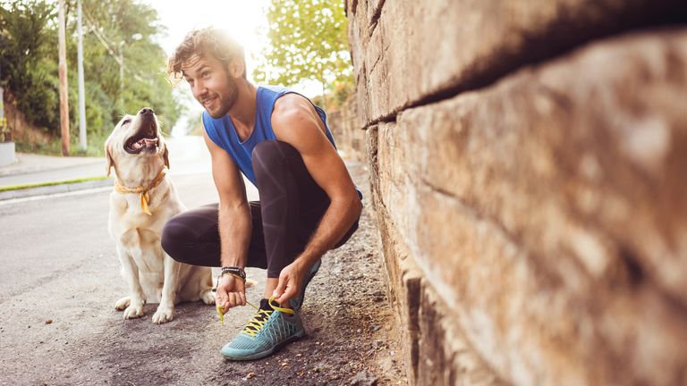 Young fit man getting ready for a run with a golden retriever by his side