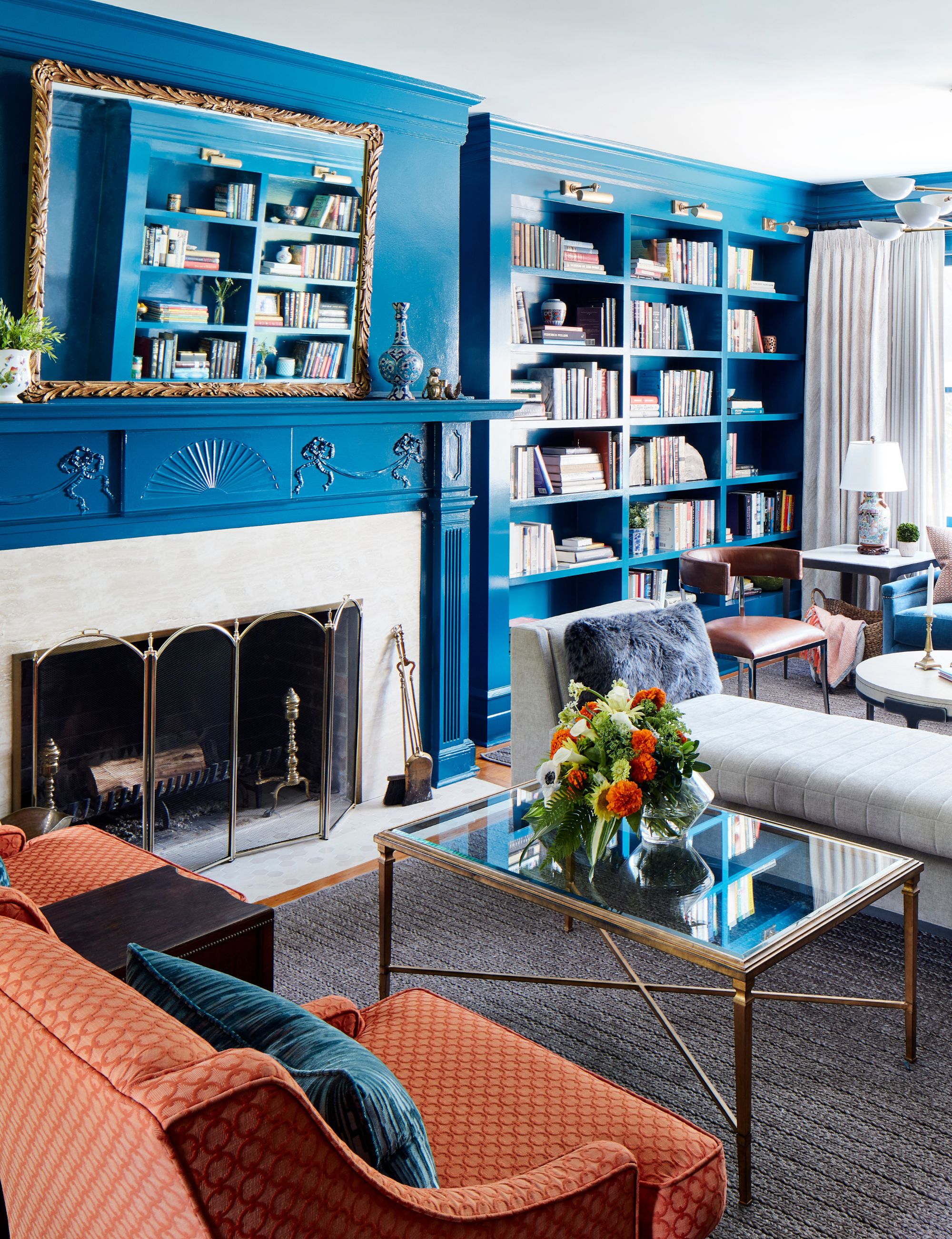 Blue high gloss living room with large fireplace, book cases and antique furniture