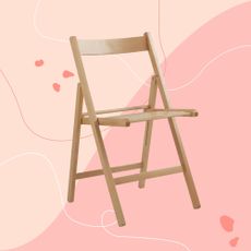 Light wooden folding chair on a pink background