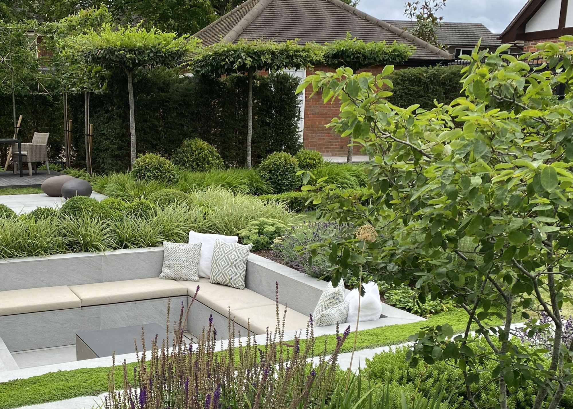 umbrellas trees and a sunken seating area in a garden