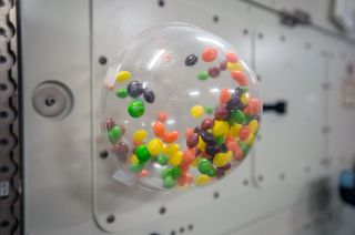 Skittles-brand fruit-flavored candies float inside a bowl in the microgravity environment on board the International Space Station in 2015.