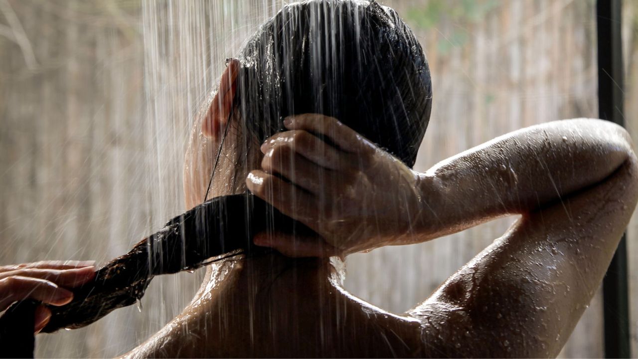 Woman washing her body and hair underneath the shower