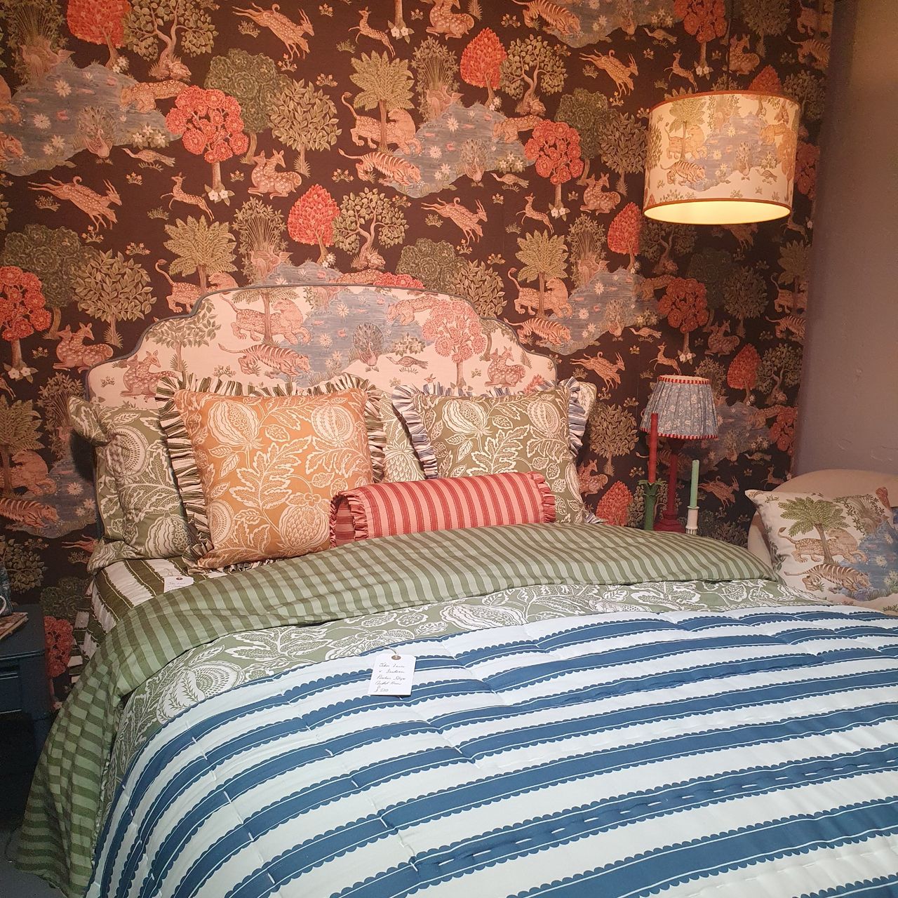 A bedroom with a Persian garden scenery-print wallpaper that's also seen on the headboard
