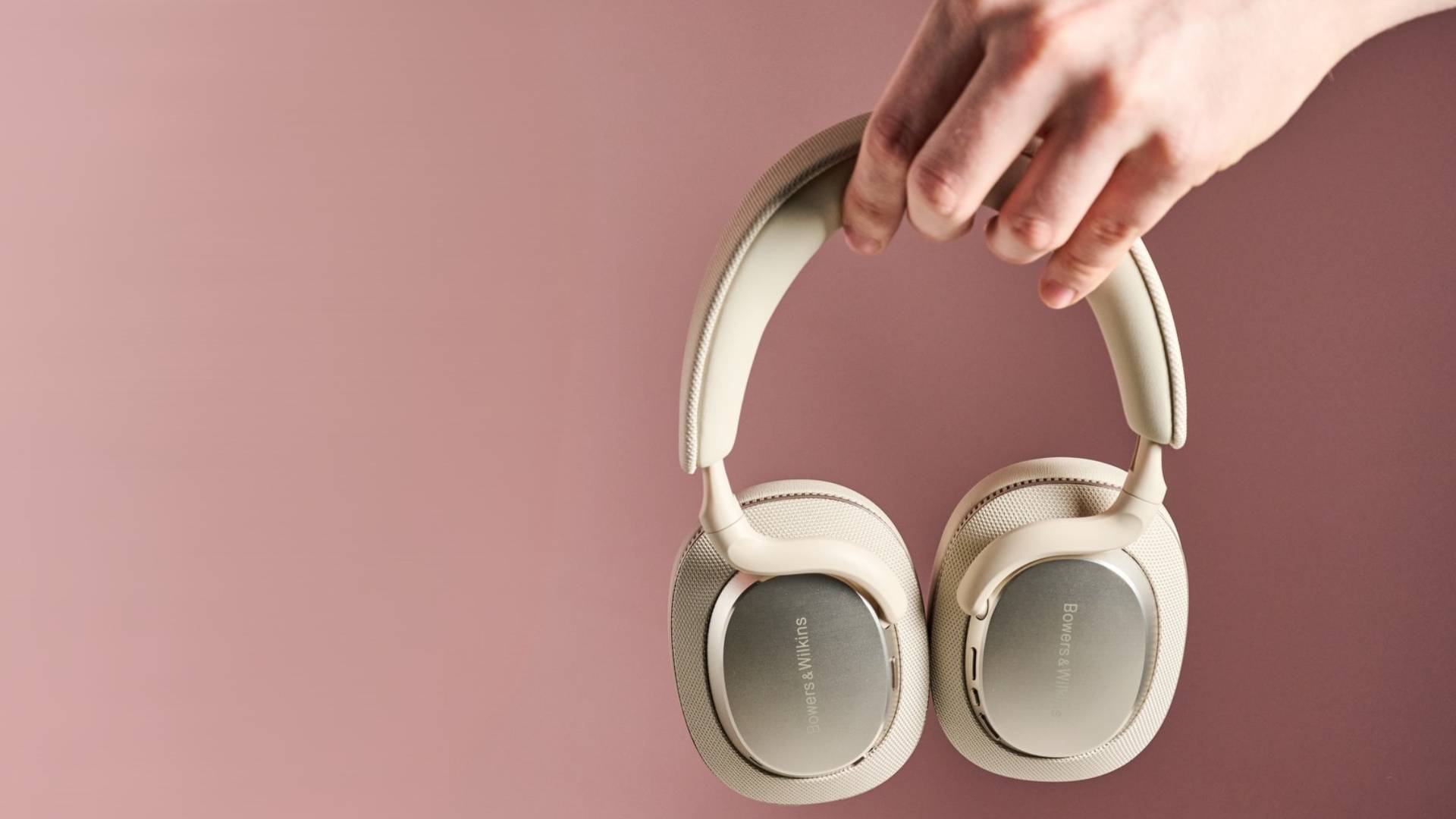 Man holding the Bowers & Wilkins Px7 S3 against pink background