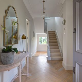 white hallway with staircase and mirror