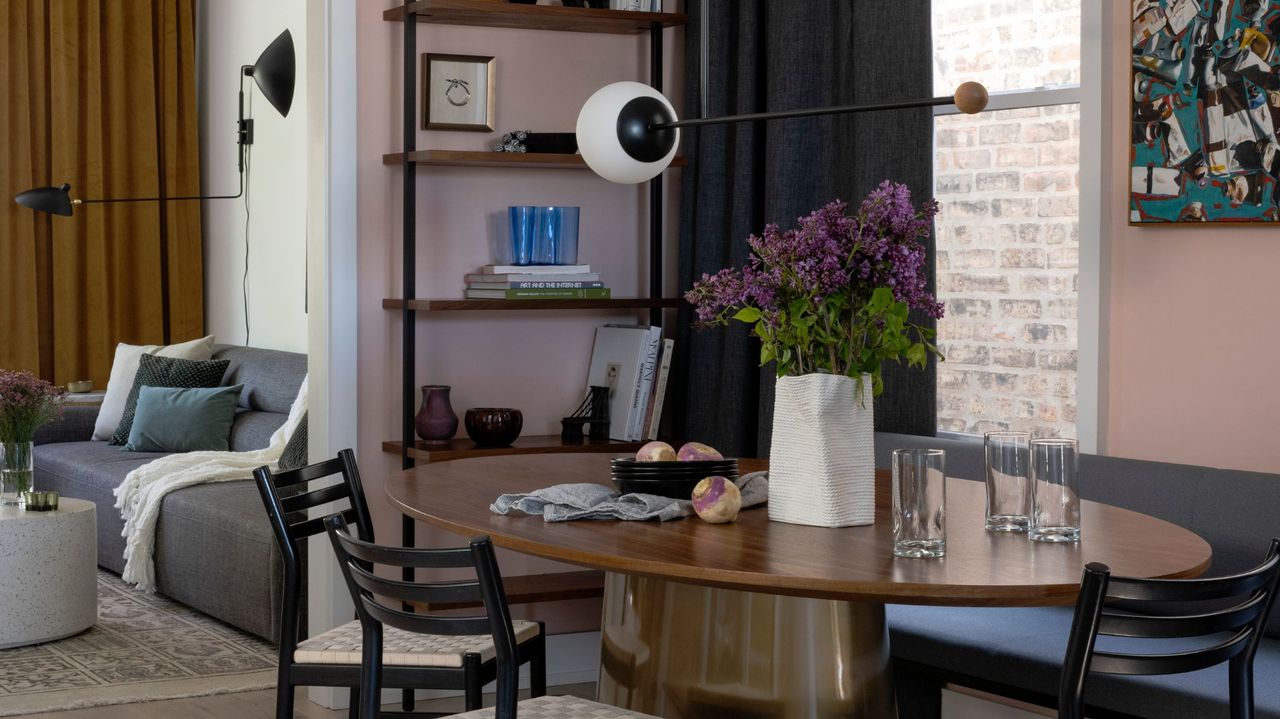 open plan dining and living space with pink walls and bookcase