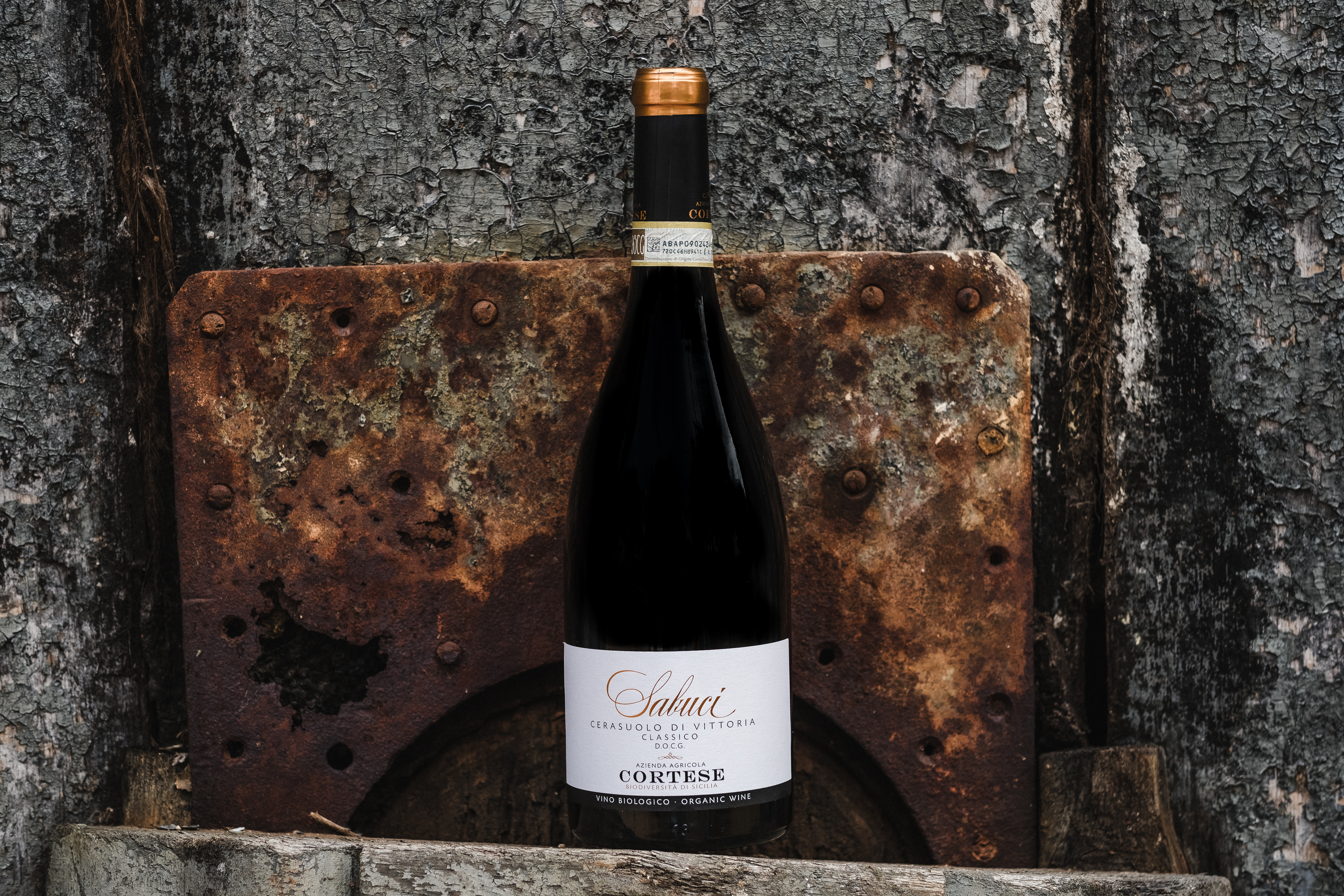 Bottle of Sabuci red wine, in front of a rusty grey wall