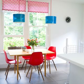 white dining area with red chairs and blue light shades
