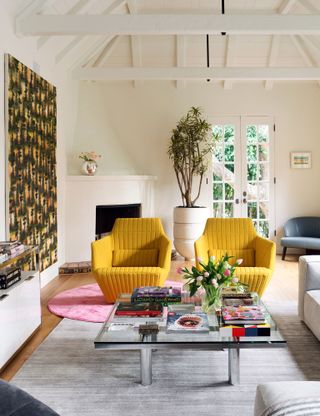 a modern living room with layered rugs and yellow armchairs