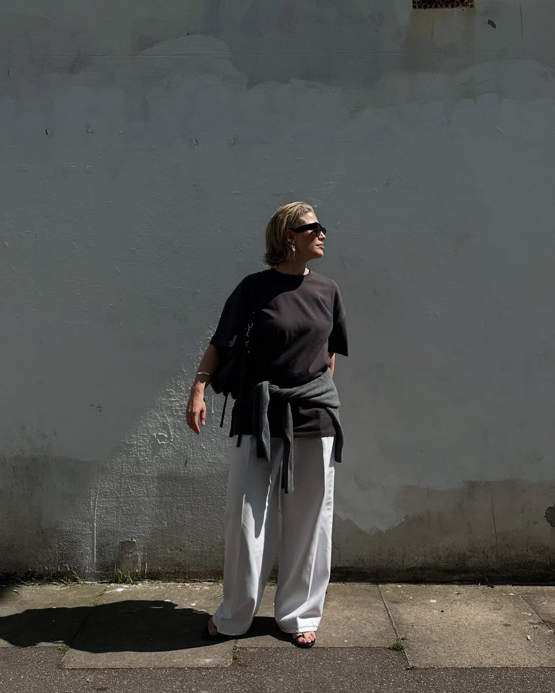 @alexisforeman wears a relaxed black tee, white jeans, sandals and sunglasses