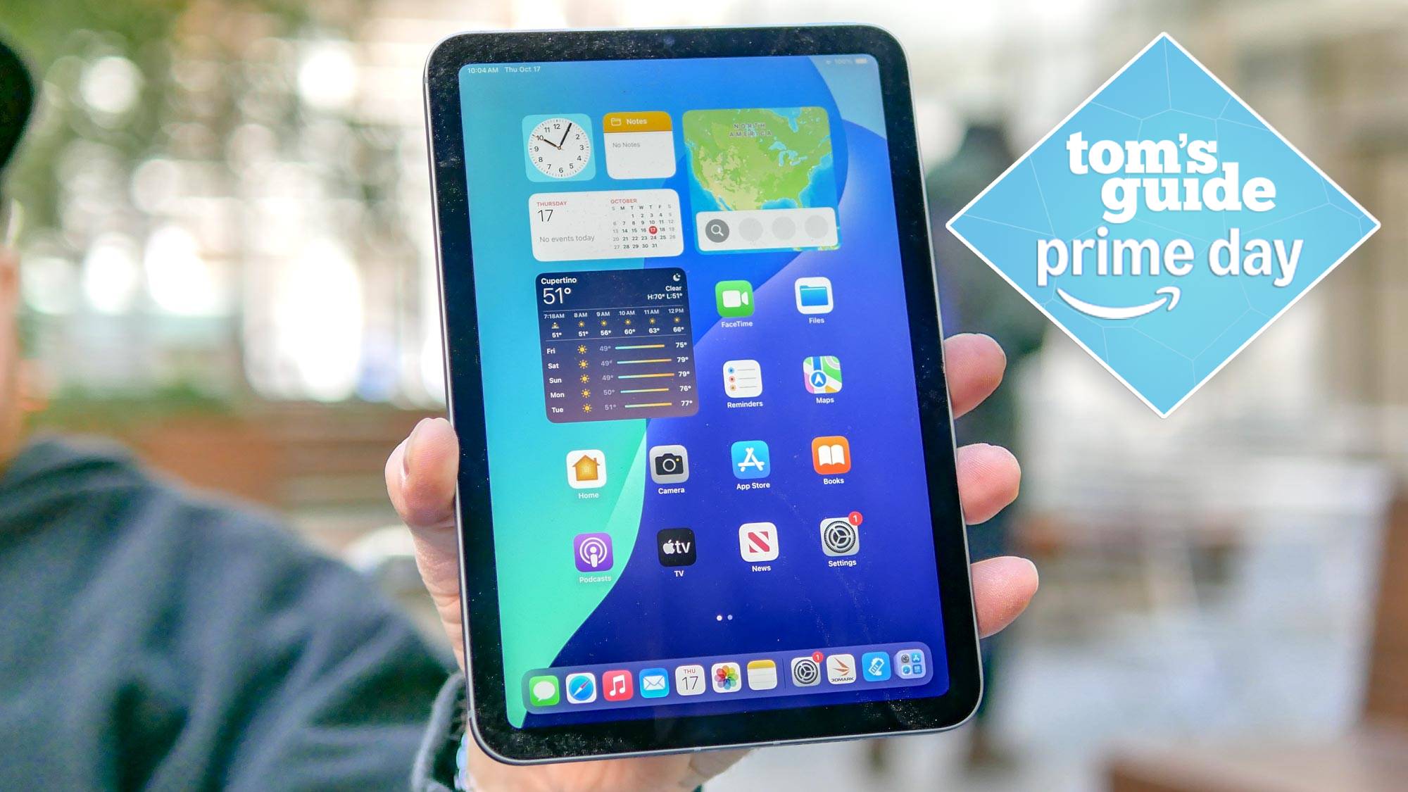 iPad mini 7 being held in hand showing front of display with Tom's Guide Prime Day badge