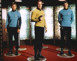 Screenshot from Star Trek showing Captain Kirk, Spock and Doctor McCoy standing in the transporter.