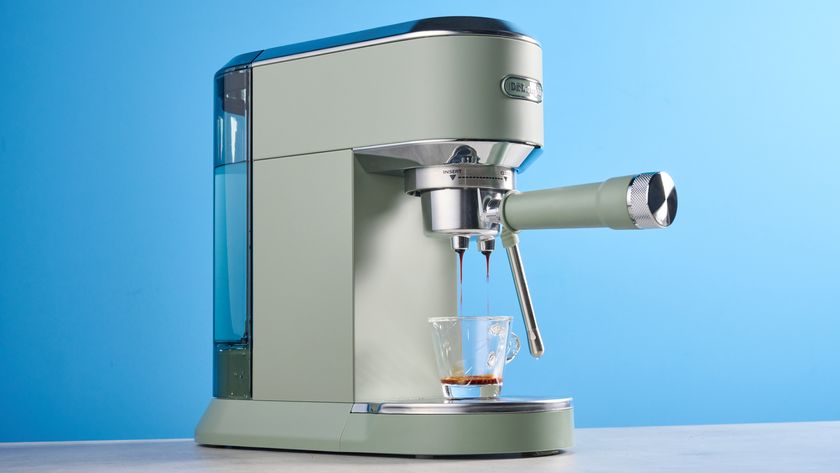 DeLonghi Dedica Duo in the green colorway with accessories photographed on a blue background. 