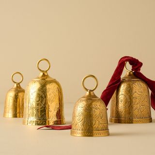 Gigi Etched Brass Bell against a gold background.