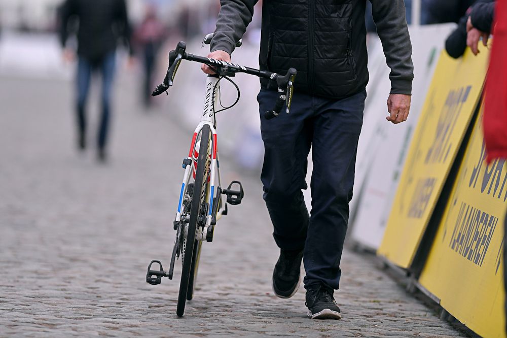 A mechanic walks Mathieu van der Poel's bike to theline after the cyclo-cross world champion crashed at Nokere Koerse