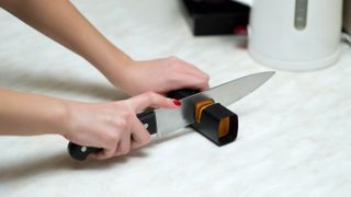 A knife being sharpened using a manual knife sharpener