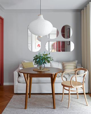 A small dining room with light gray walls, and a white sofa