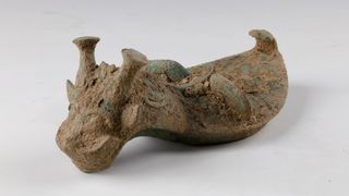 This bronze cover for a pottery vessel seems to have their cast in the shape of a horned dragon