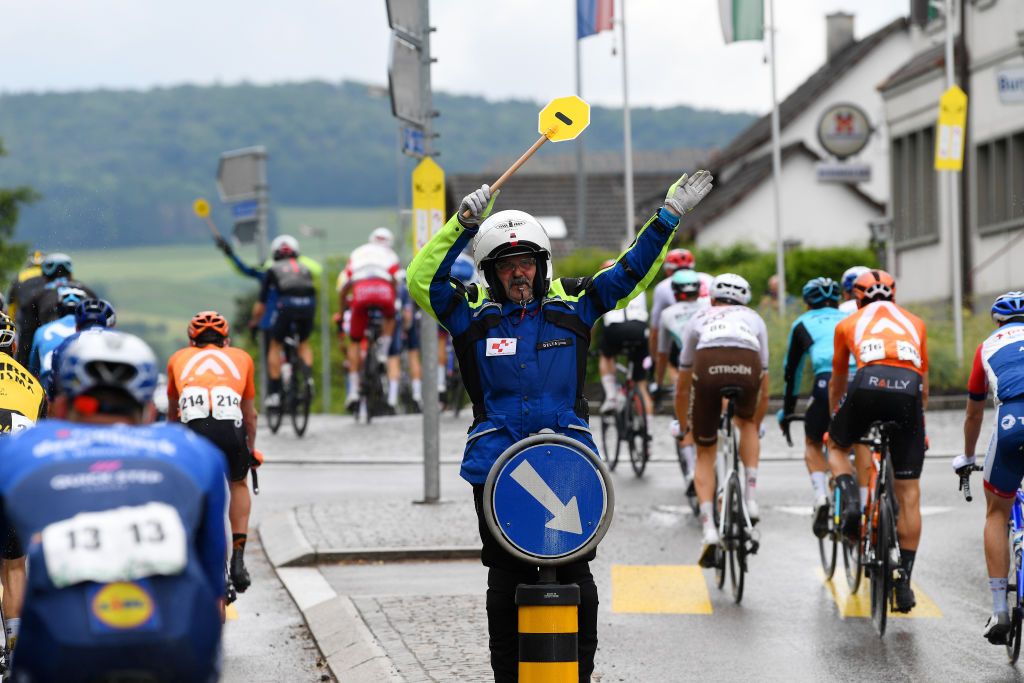 LACHEN SWITZERLAND JUNE 07 Security officer guides the peloton during the 84th Tour de Suisse 2021 Stage 2 a 178km stage from Neuhausen am Rheinfall to Lachen Safety Landscape UCIworldtour tds tourdesuisse on June 07 2021 in Lachen Switzerland Photo by Tim de WaeleGetty Images