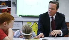 Britain's Prime Minister David Cameron reads a book to Lucy Howarth, 6, (L), and Will Spibey, 5, during a visit to Sacred Heart RC primary school in Westhoughton near Bolton on April 8, 2015.