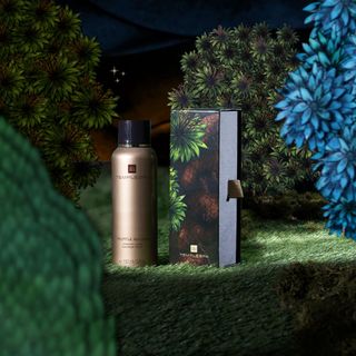 A bottle of Templespa Truffle Mousse shower foam pictured beside its packaging on a backdrop inspired by a Mediterranean garden at night