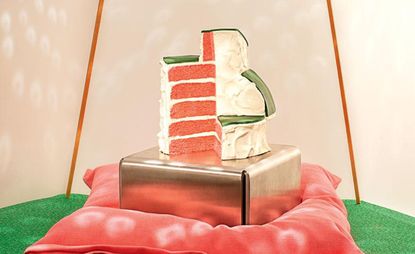 A cake slice, set on a metal pedestal, below a disco ball.