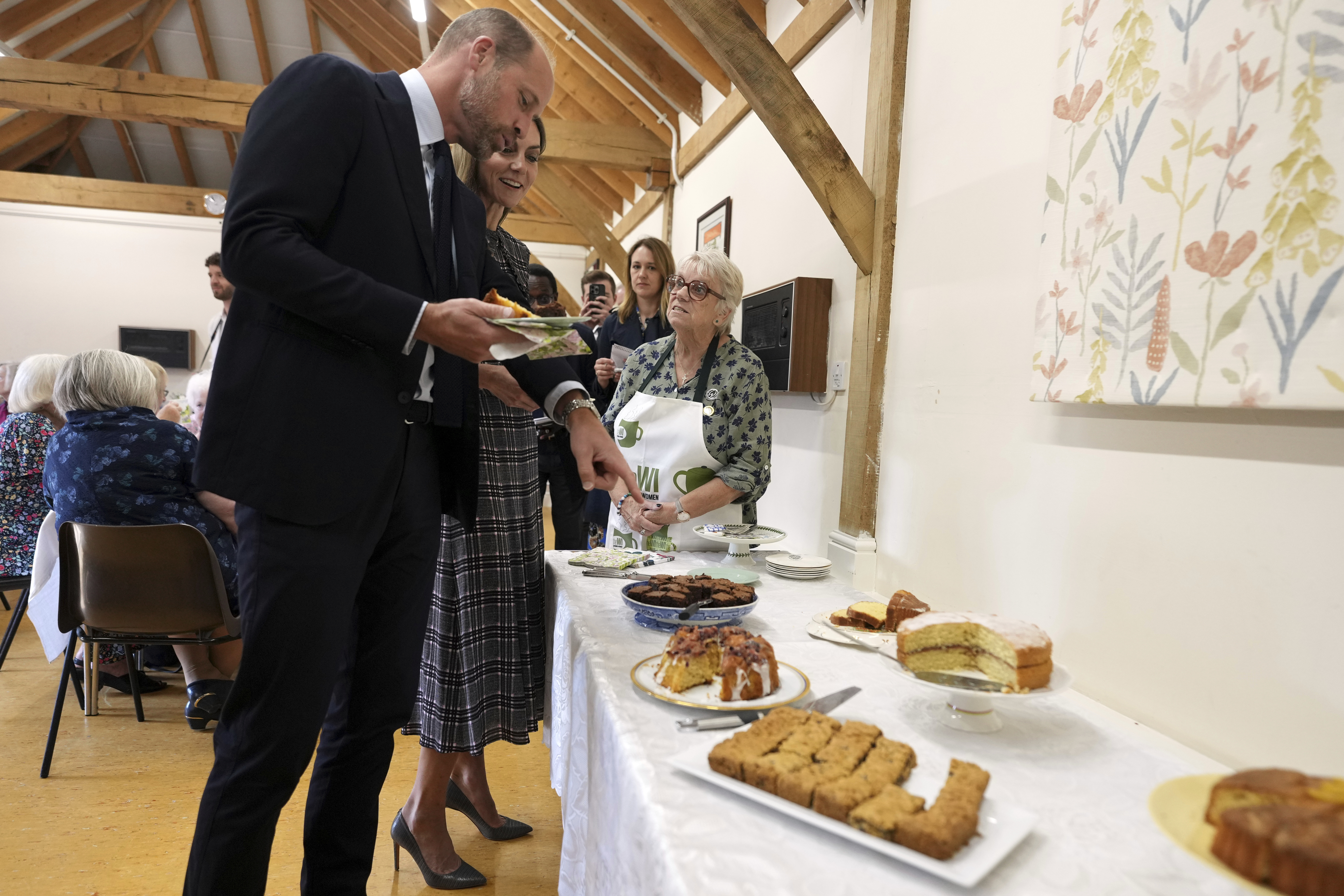Prince William and Princess Kate selecting desserts from a long table