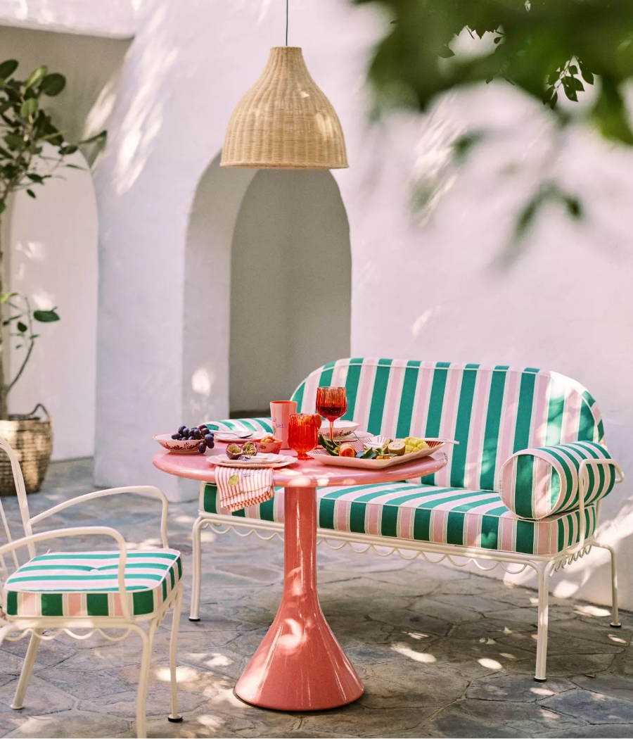 a pink and green striped outdoor sofa with a red table in a courtyard