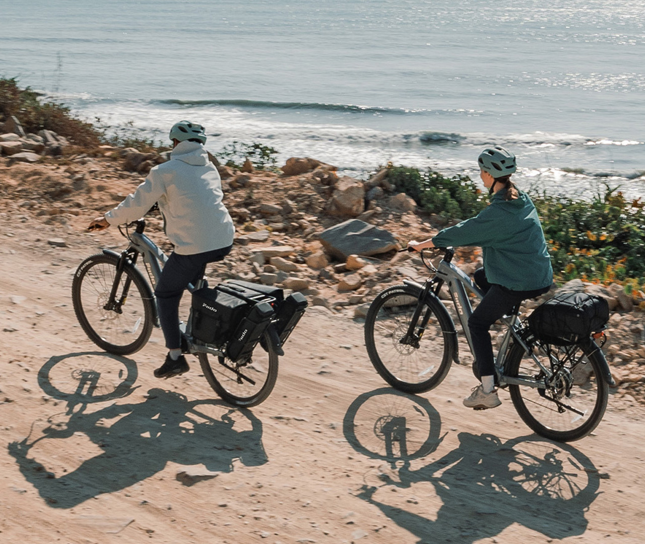 Two people riding Fiido Nomads Pro electric bikes overlooking the sea