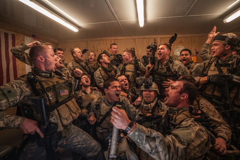 A group of soldiers in full gear singing and laughing.