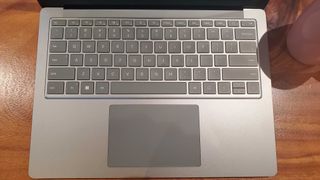 Lähikuvassa puisella pöydällä oleva hopeinen Surface Laptop 5
