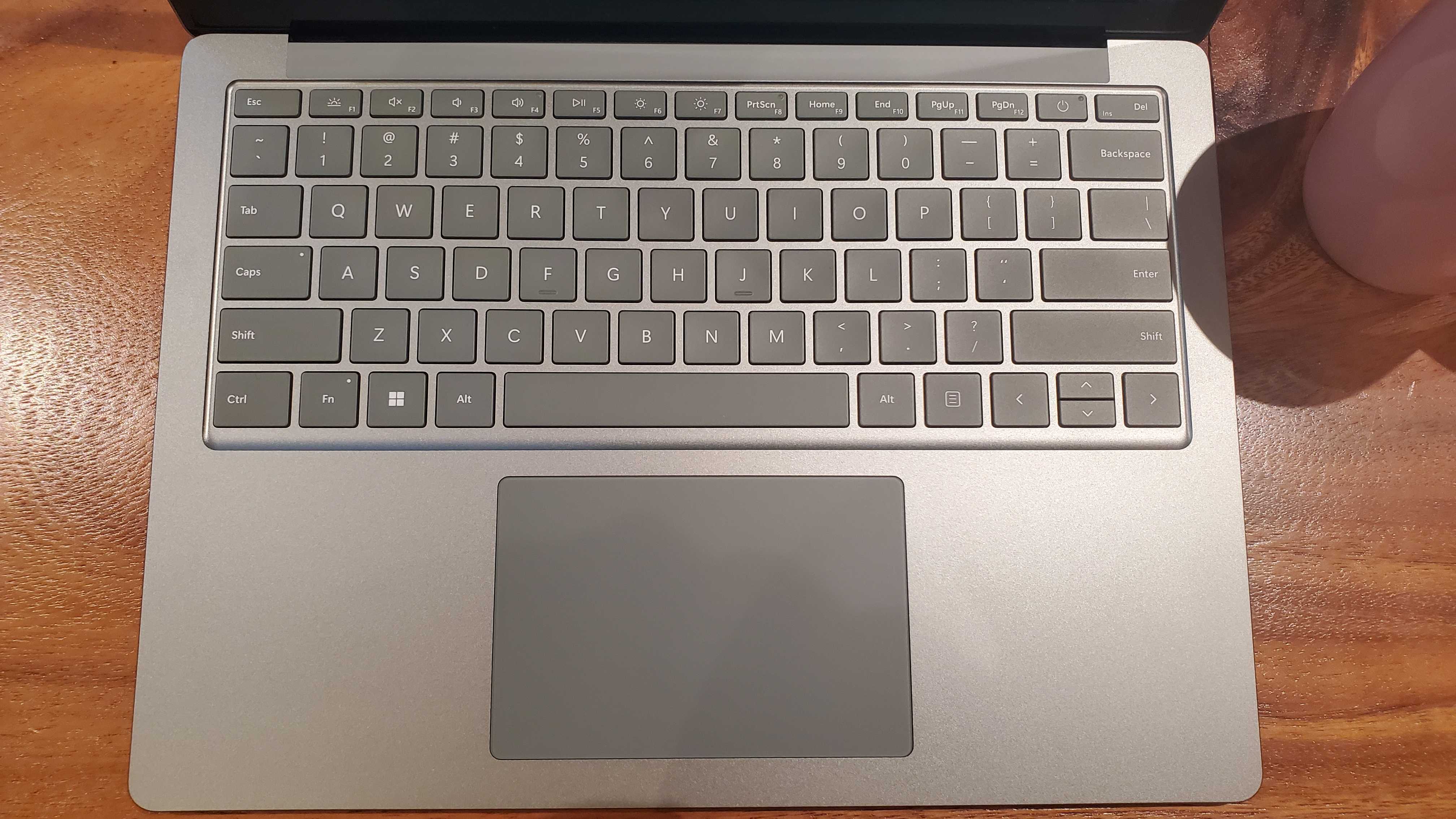 Lähikuvassa puisella pöydällä oleva hopeinen Surface Laptop 5