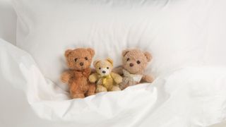 Three teddy bears in a bed
