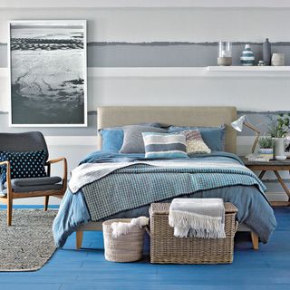 bedroom with white and grey wall and grey bed with blue cushions
