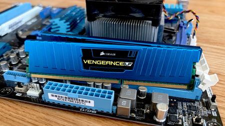 Blue Corsair Vengeance LP DDR3 RAM sitting on a motherboard with CPU cooler in the background.