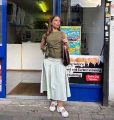 Influencer @daughterofahoarder wears velcro trainers with a sage cotton skirt and a dark green top.