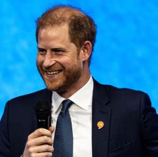 Prince Harry wearing a suit and speaking into a mic