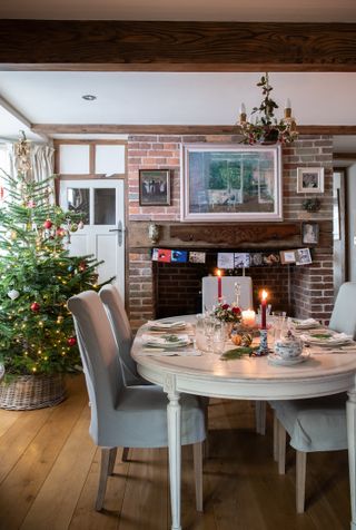 Christmas dining table set with candles and vintage china and textiles and christmas tree in background