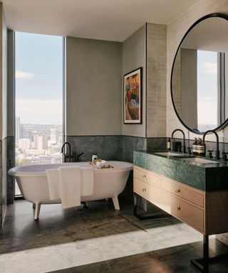 Double bathroom vanity in apartment bathroom with bath and view of city behind