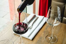 A glass of red wine being poured at a restaurant