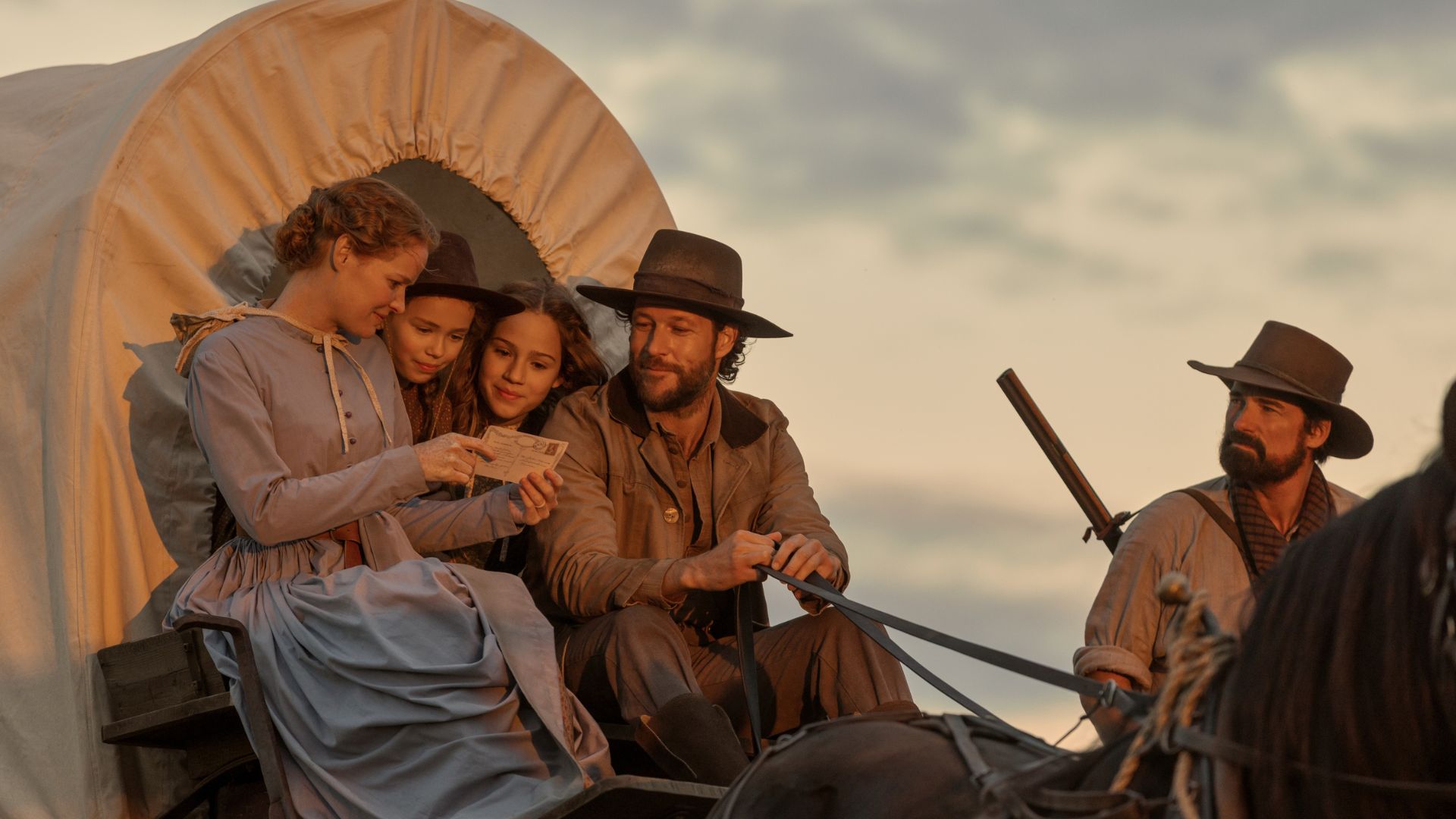 The Ingalls family look at a letter while sitting in a wagon