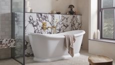 A bathroom with purple marble accents, a large free-standing white tub, and herringbone floor tiles