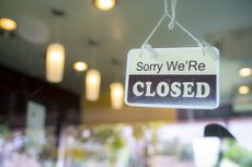 Closed sign hanging on glass door in small business window.