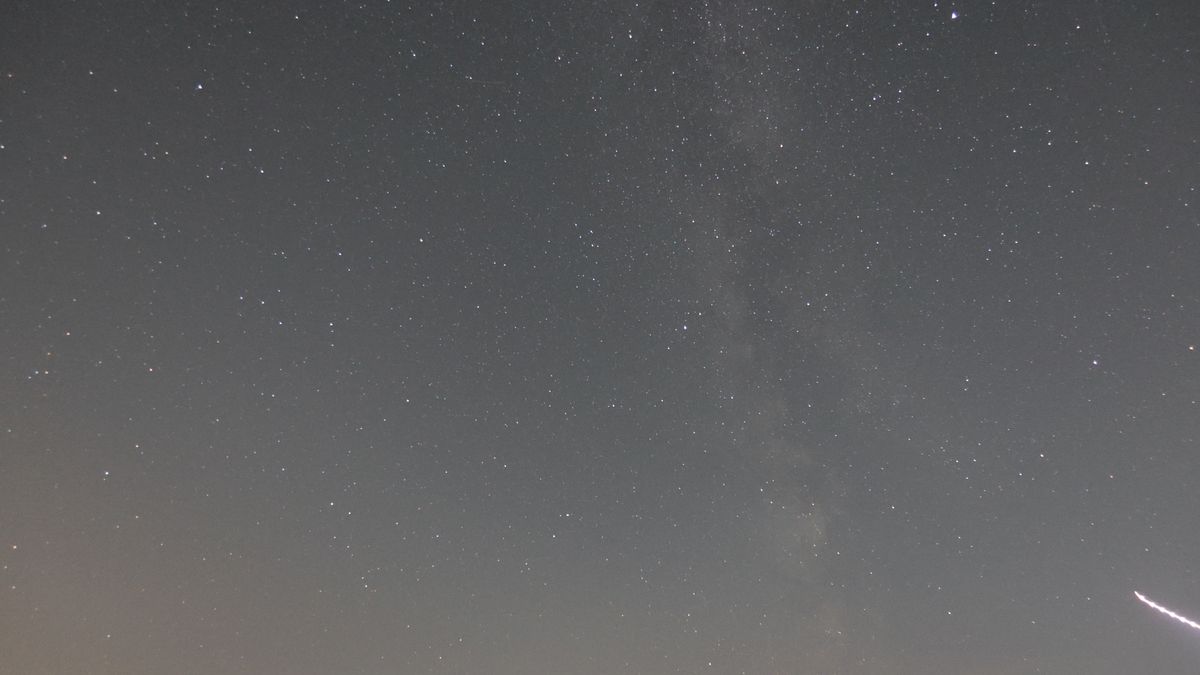 An astrophoto showing the core of the Milky Way and a light streak from an airplane, taken with the Canon Powershot V1.